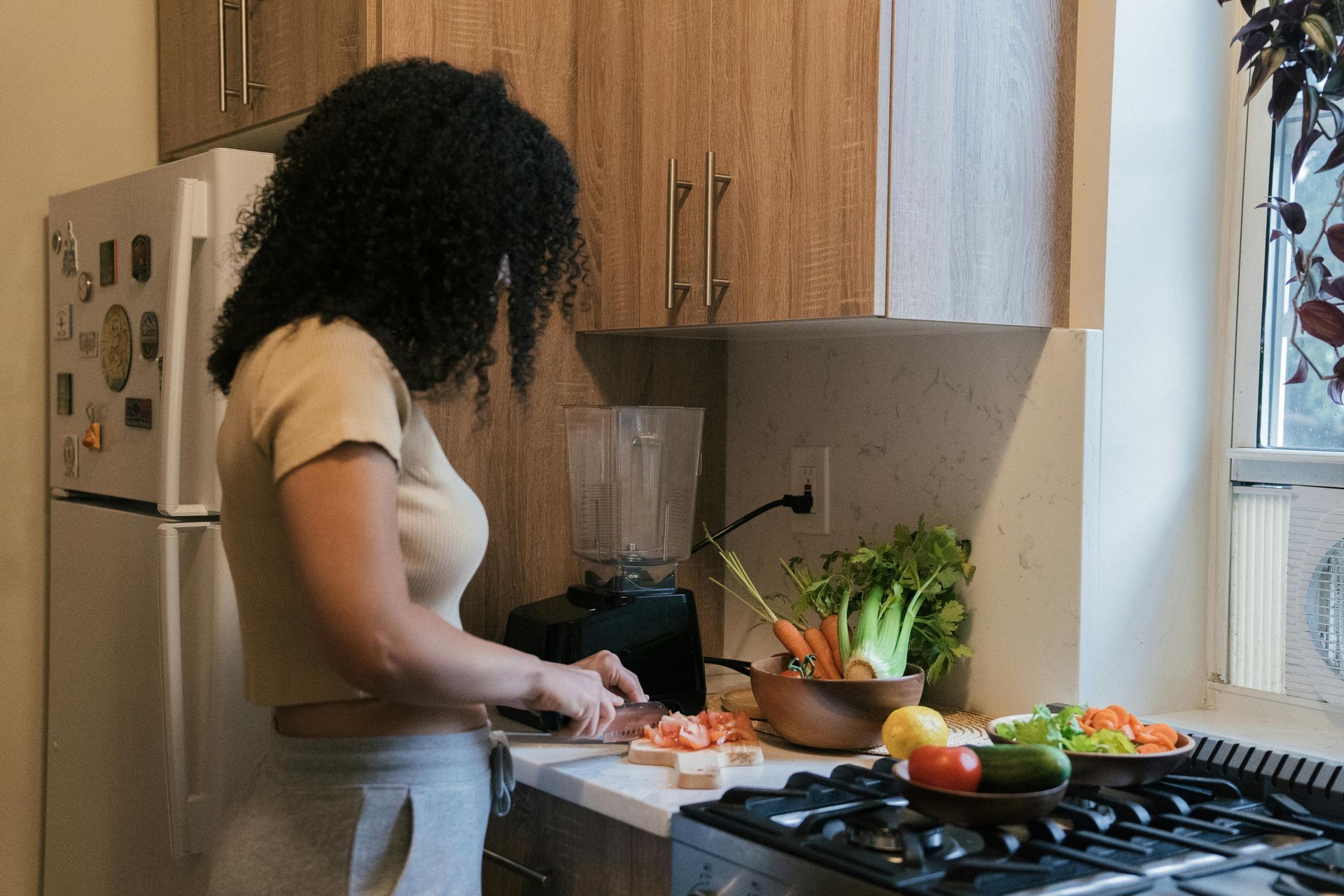 Woman in kitchen cutting vegetables for blending  — All Body Holistic Health in Thuringowa Central, QLD