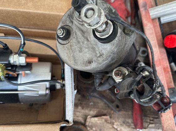 A close up of a car engine with a lot of wires coming out of it.