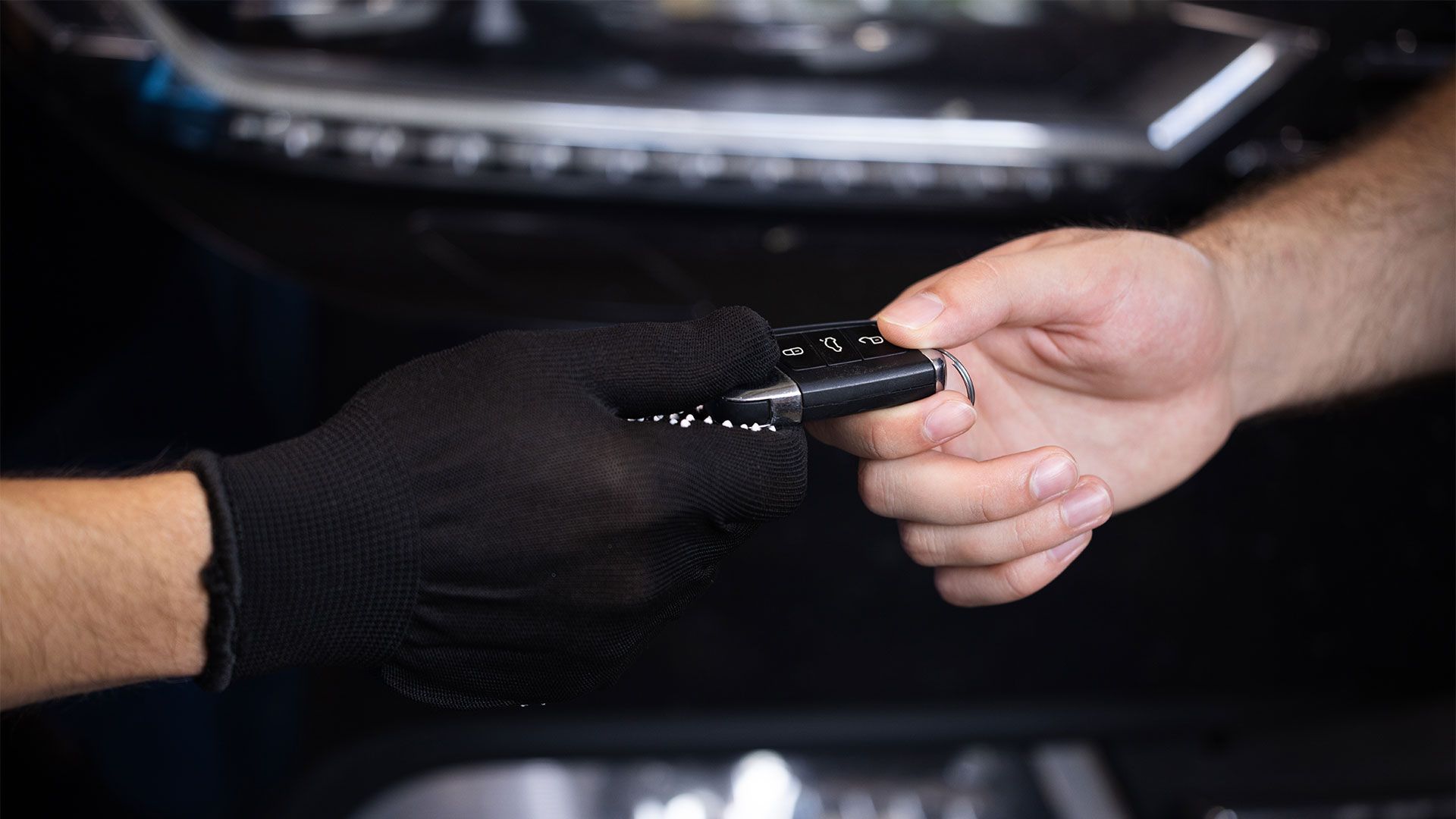 A man wearing black gloves is holding a black object in his hand.