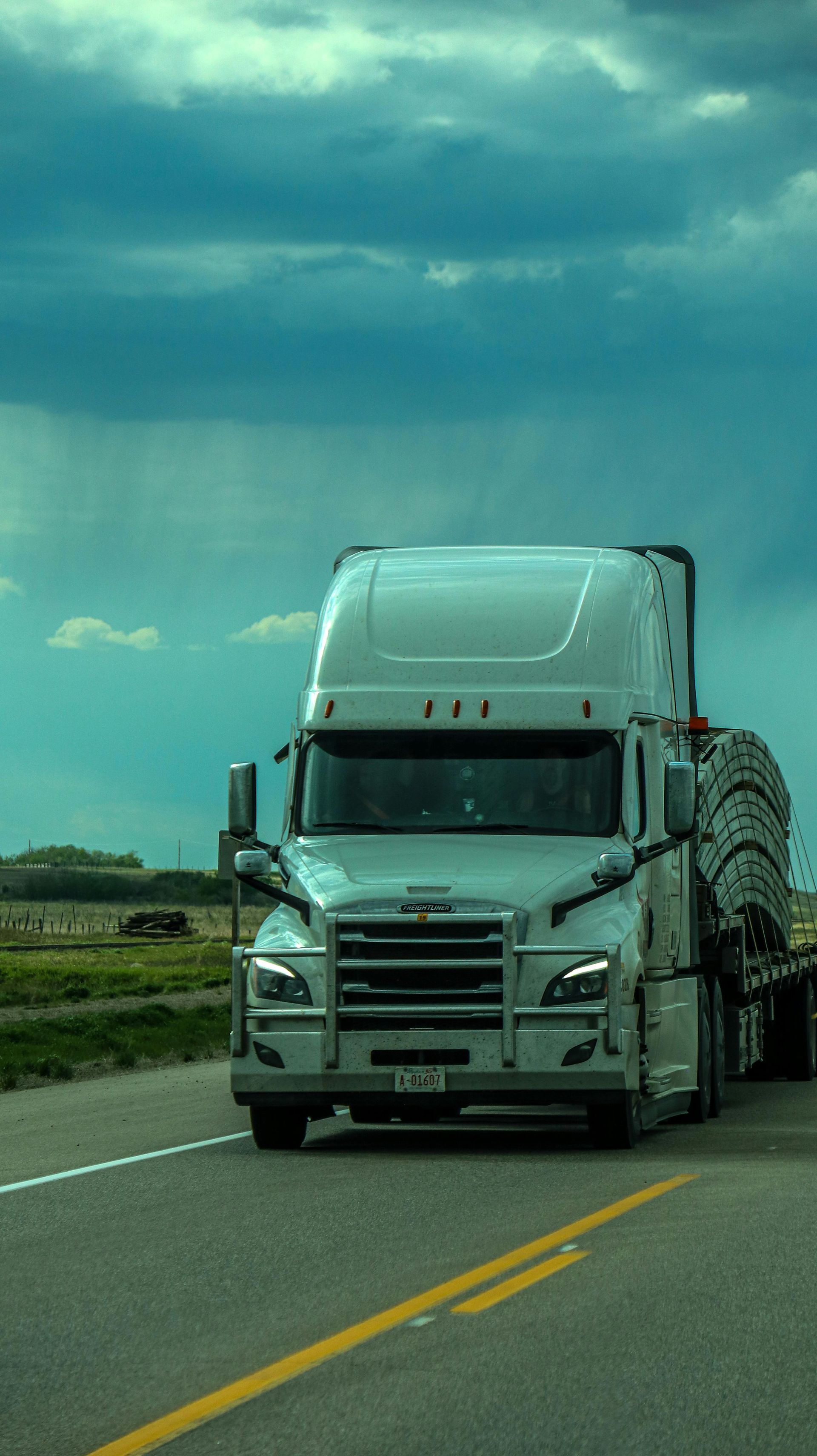 A white semi truck is driving down a highway.