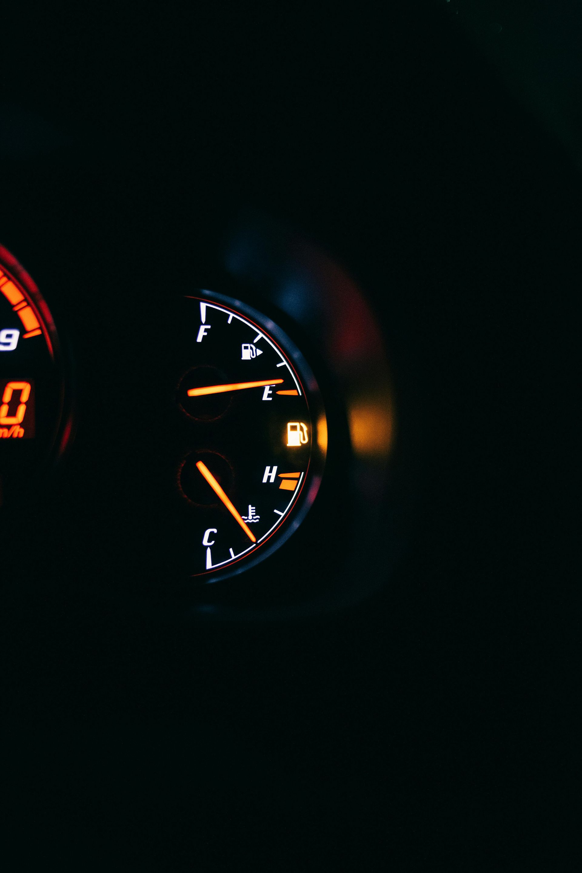 A close up of a fuel gauge in a car in the dark.