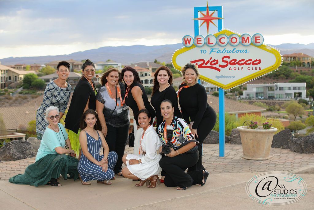 A group of women are posing for a picture in front of a welcome sign.