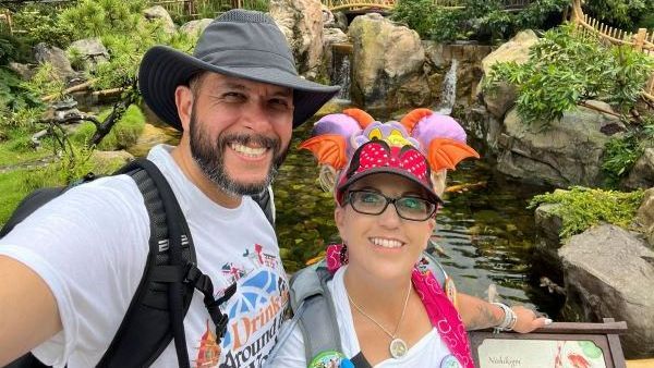 A man and a woman are posing for a picture in front of a waterfall.