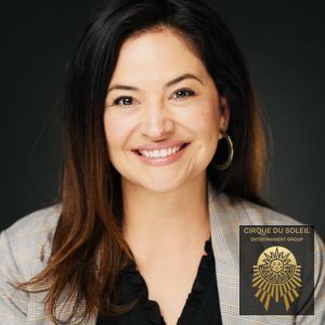 A woman is smiling in front of a cirque du sole logo