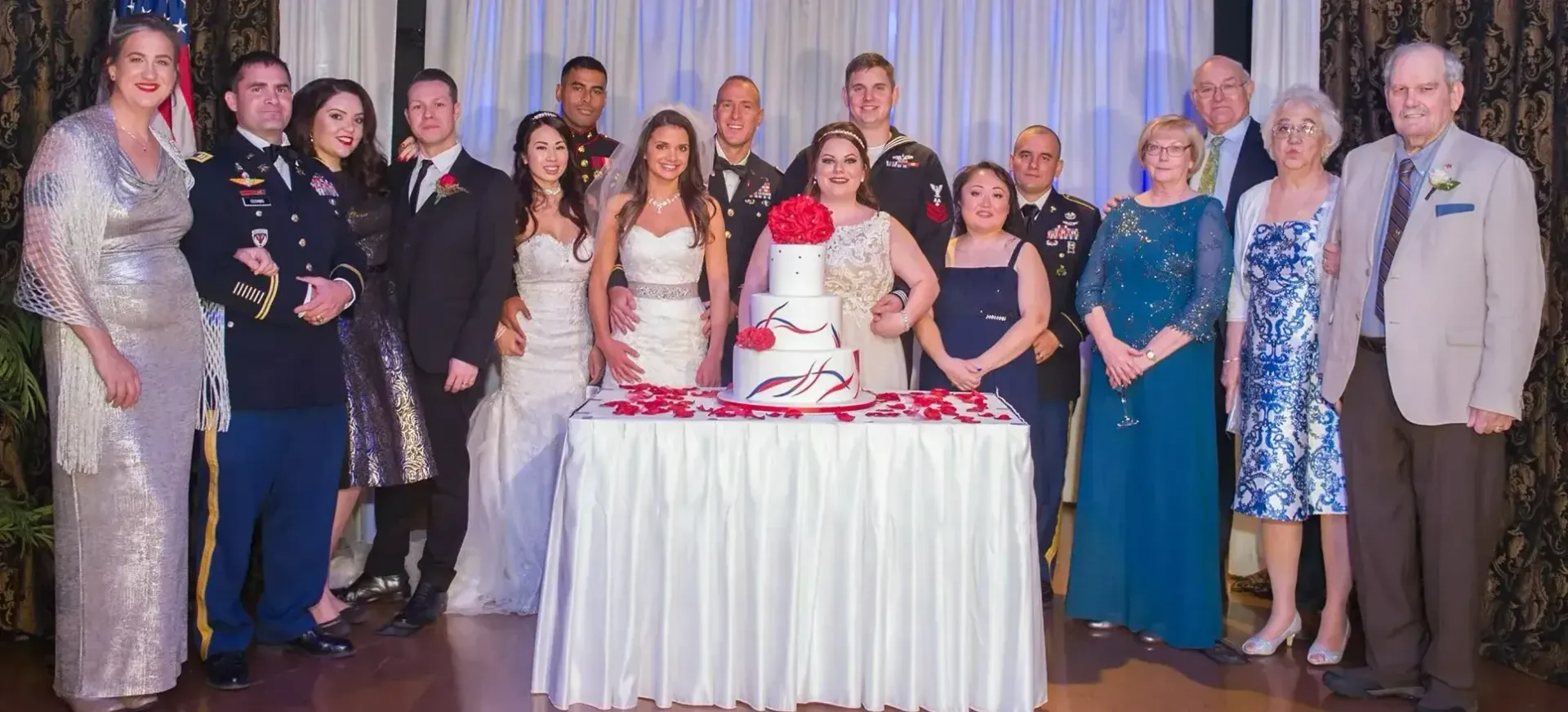 A group of people are posing for a picture in front of a wedding cake.