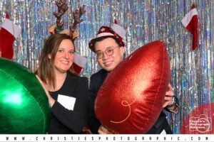 A man and a woman are holding balloons in a photo booth.
