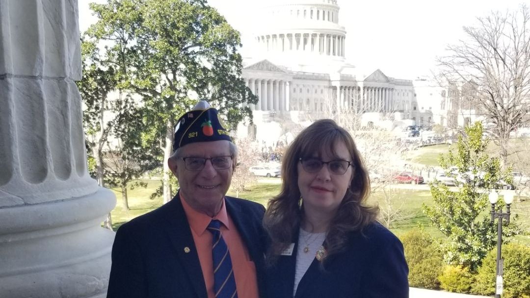 A man and a woman are posing for a picture in front of the capitol building.