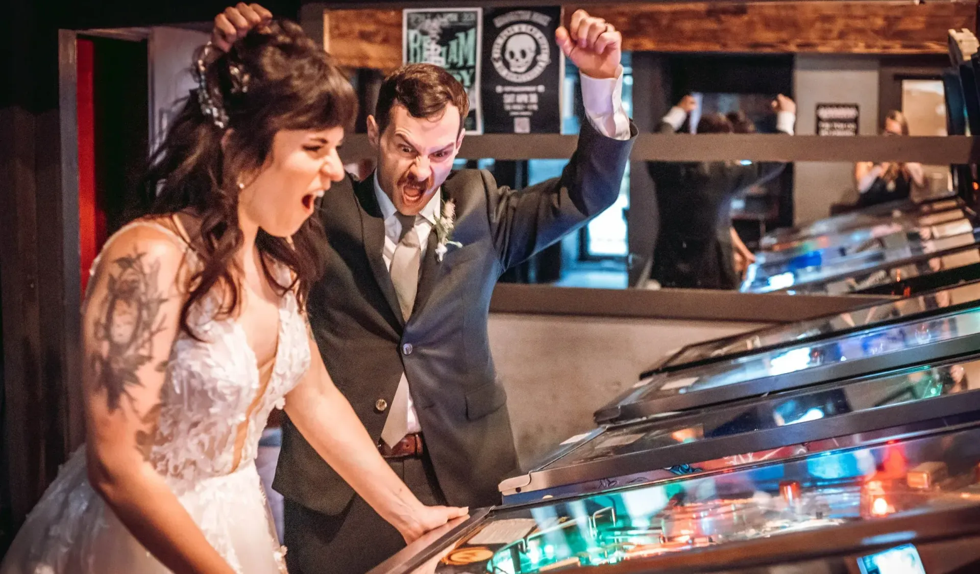A bride and groom are playing pinball at their wedding reception.