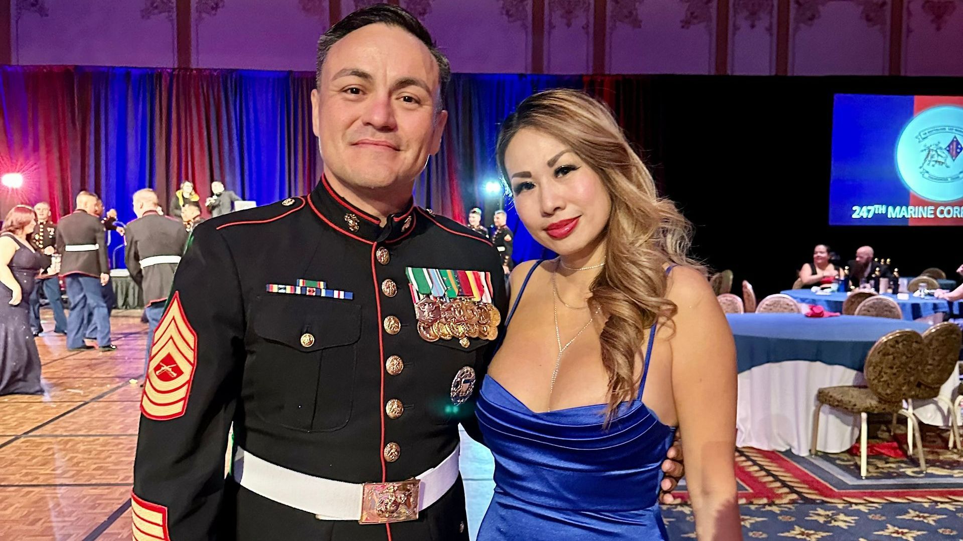 A man in a military uniform and a woman in a blue dress are posing for a picture.