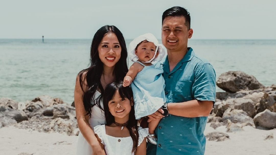 A family is posing for a picture on the beach.