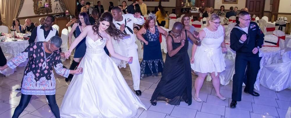A bride and groom are dancing with their guests at a wedding reception.