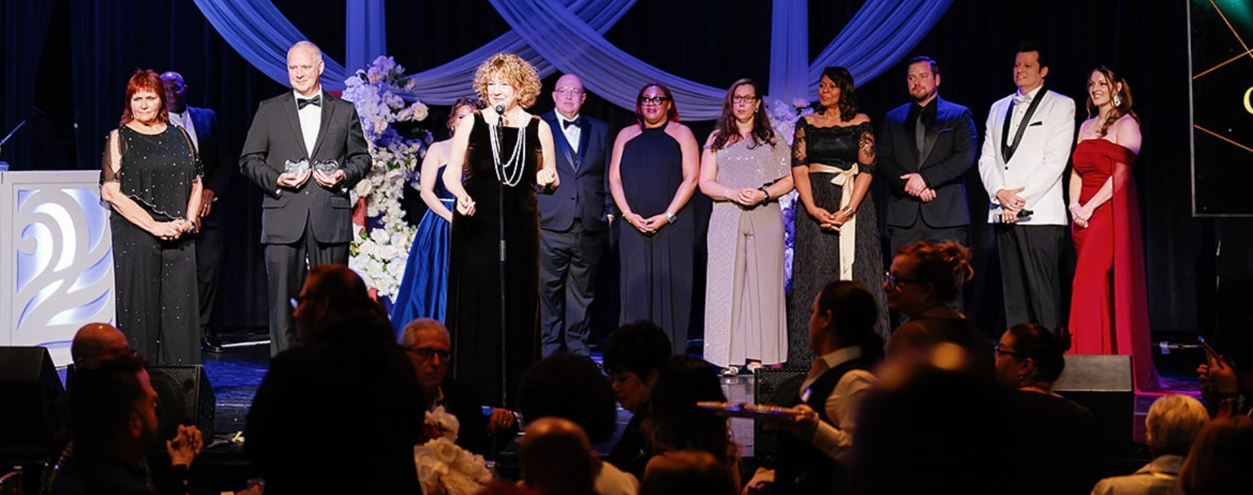 A group of people are standing on a stage in front of a crowd.