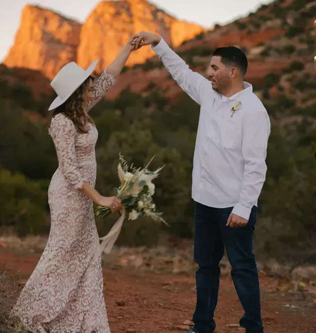 A bride and groom are dancing in front of a mountain.