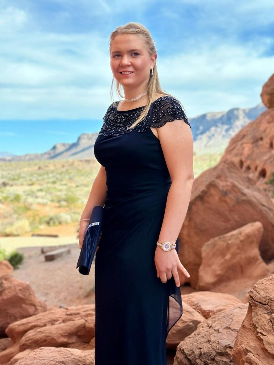 A woman in a black dress is standing in front of a mountain.