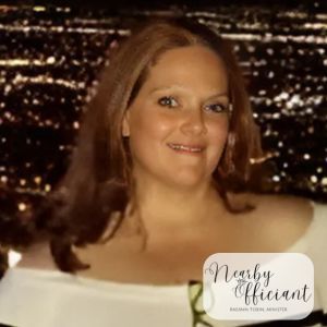Woman with reddish-brown hair smiling; light-colored top; background of city lights;