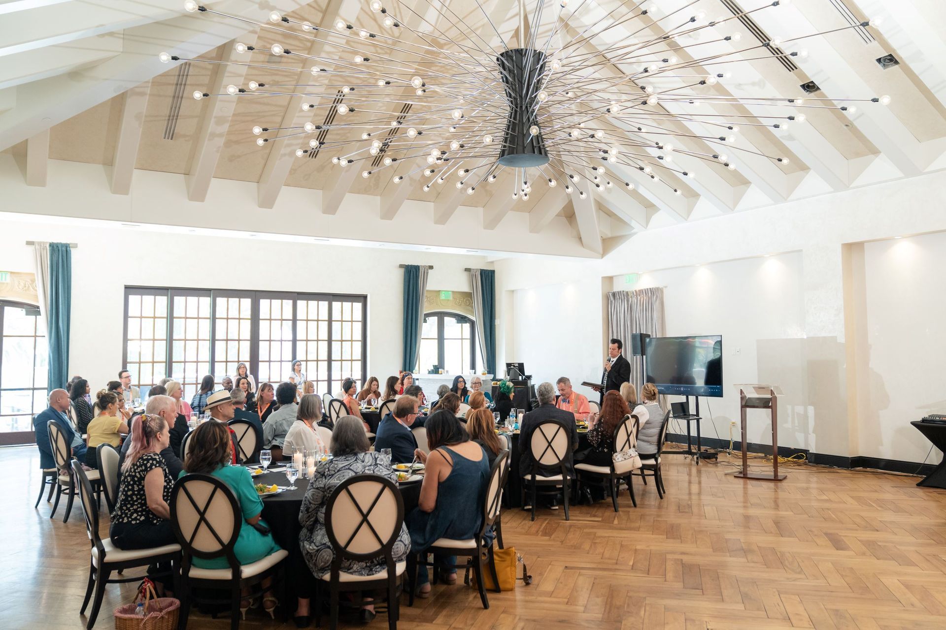 A group of people are sitting at tables in a large room.