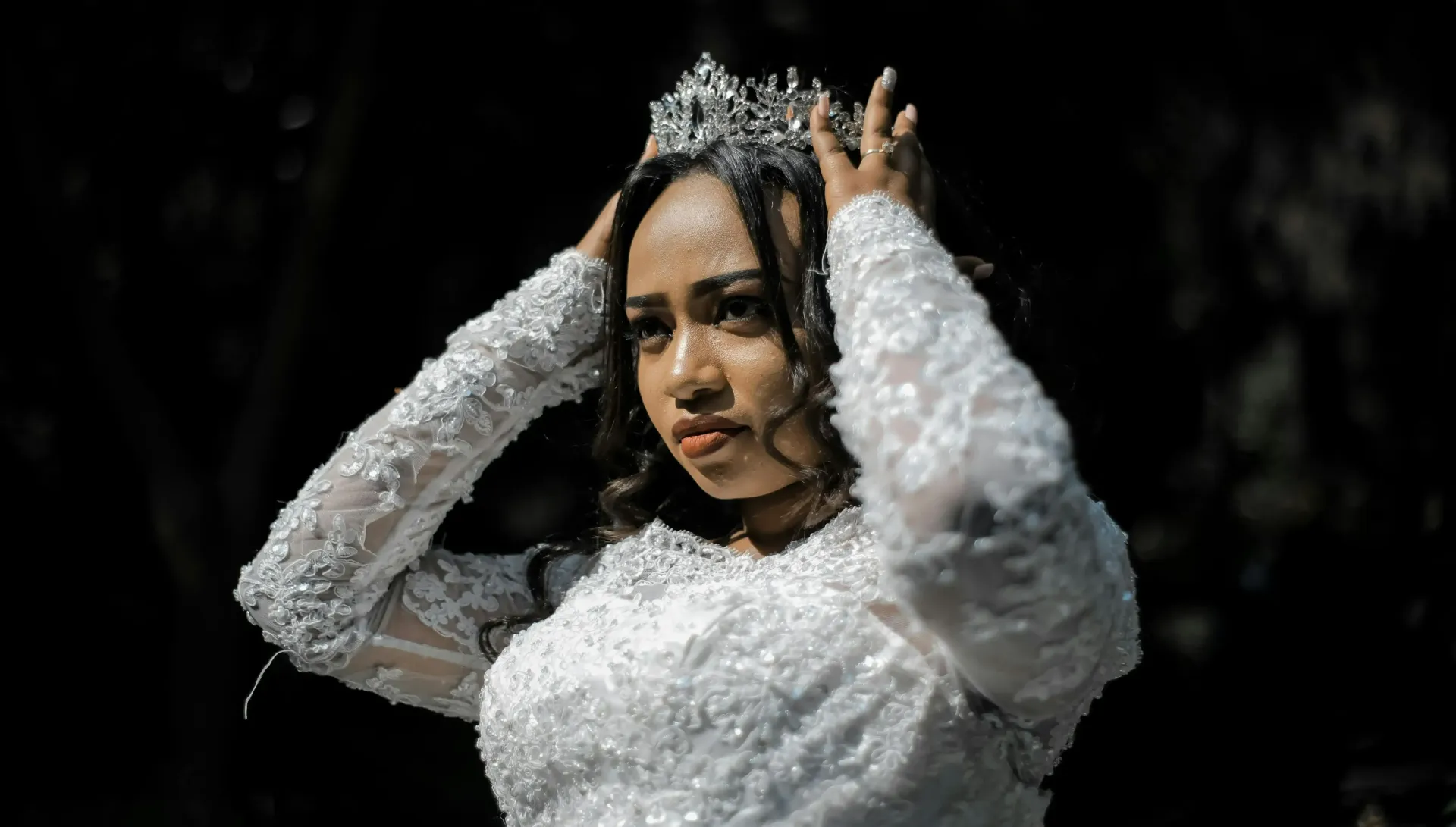 A woman in a wedding dress is wearing a tiara on her head.