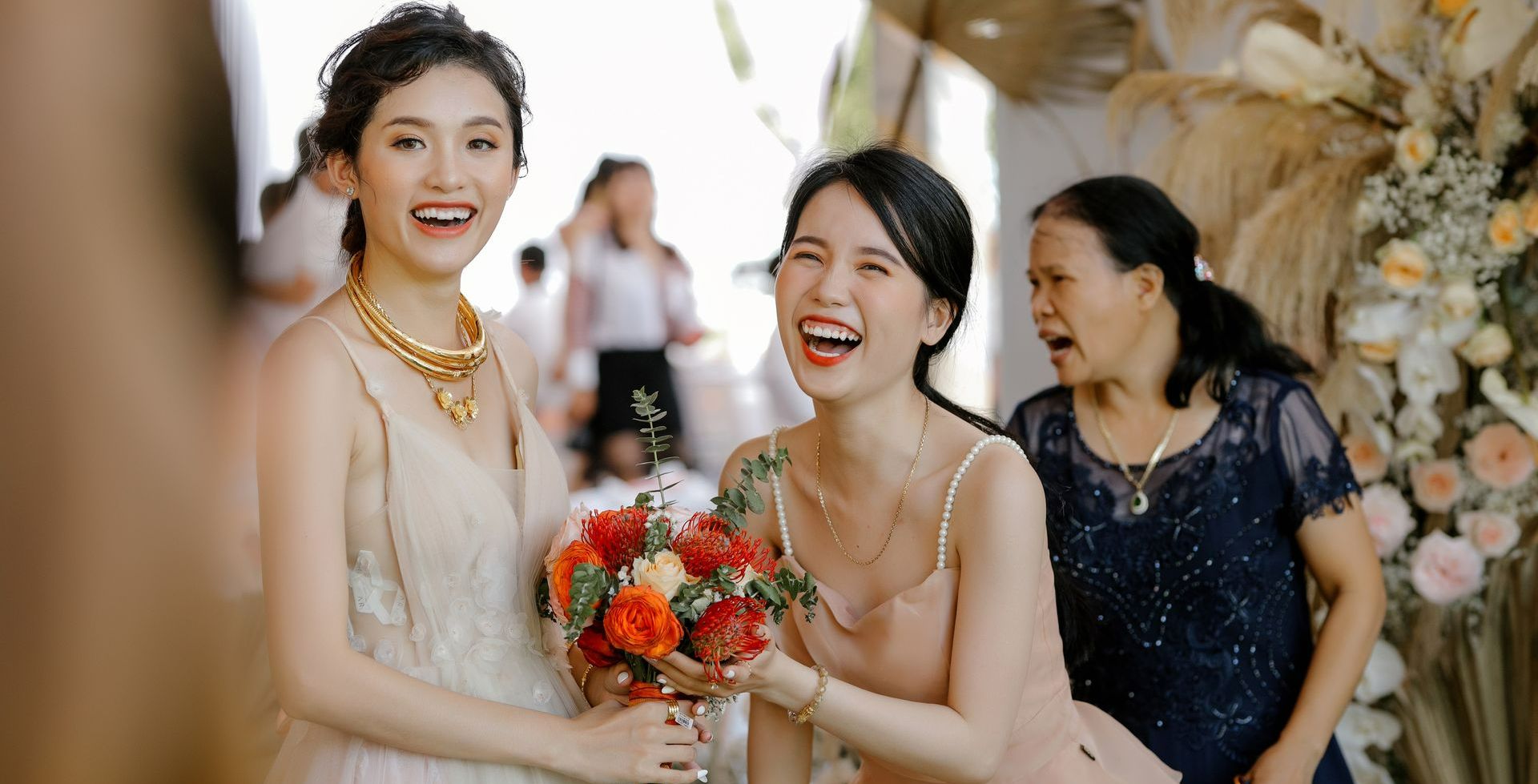 A bride is holding a bouquet of flowers and laughing with her bridesmaids.