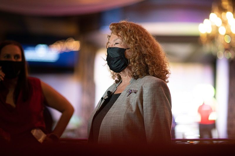 A woman wearing a mask is standing next to another woman.