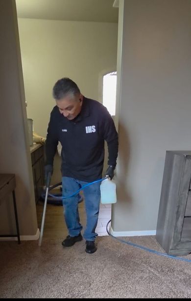 Man vacuuming carpet in a doorway between rooms, holding a vacuum hose in a home interior