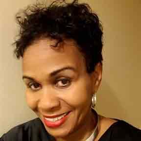 Smiling person with short curly hair, red lipstick, and hoop earrings against a beige background