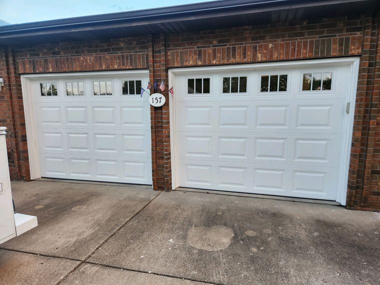 Suburban two-car garage with white doors and a wide concrete driveway