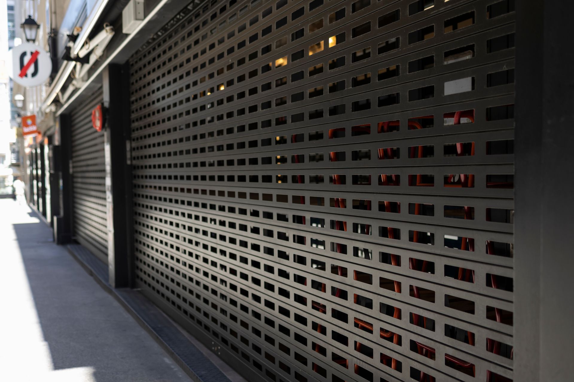 Closed metal storefront shutters along a city sidewalk in daylight