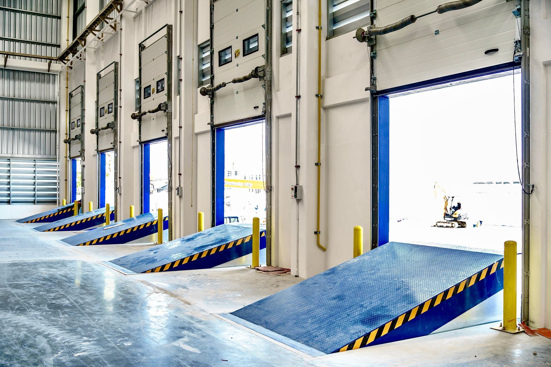Warehouse loading dock with blue ramps and open bay doors