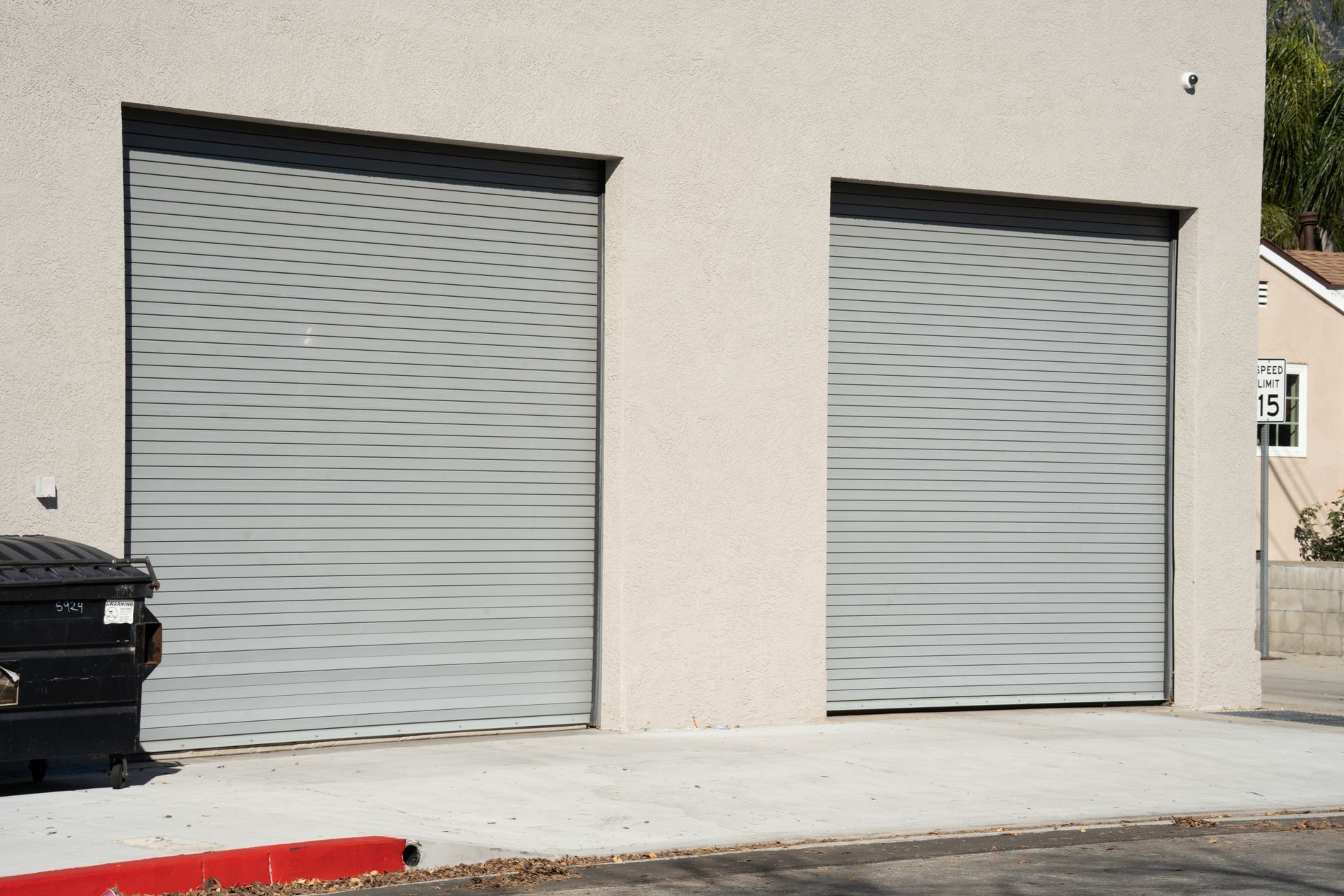 Empty loading dock with five closed white and black truck bays and yellow pavement lines