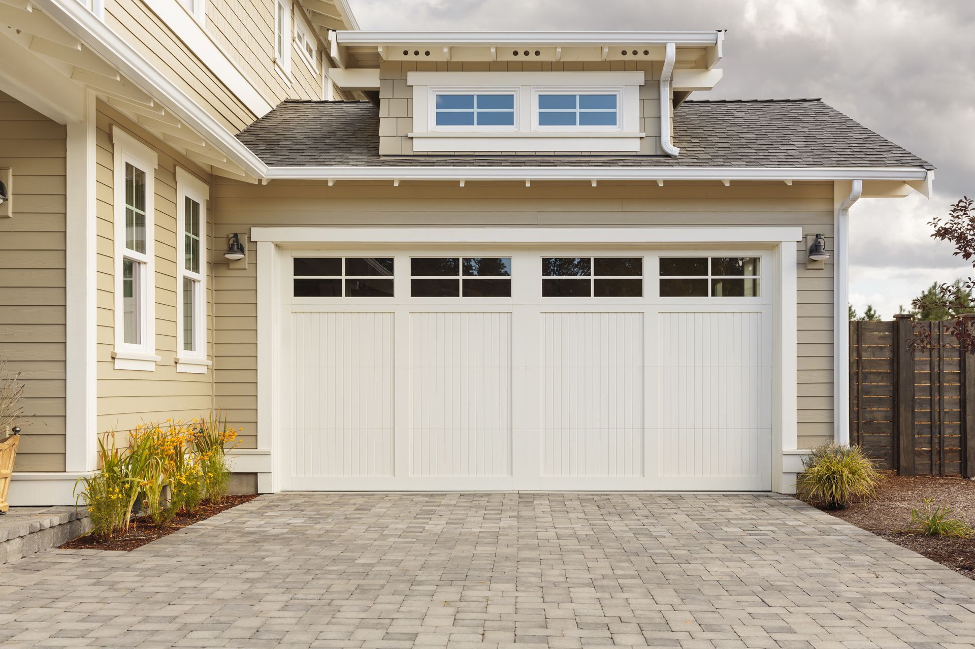 White double garage door on a beige house with stone driveway and small front windows