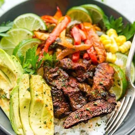 A close up of a bowl of food with meat , rice , avocado and vegetables.