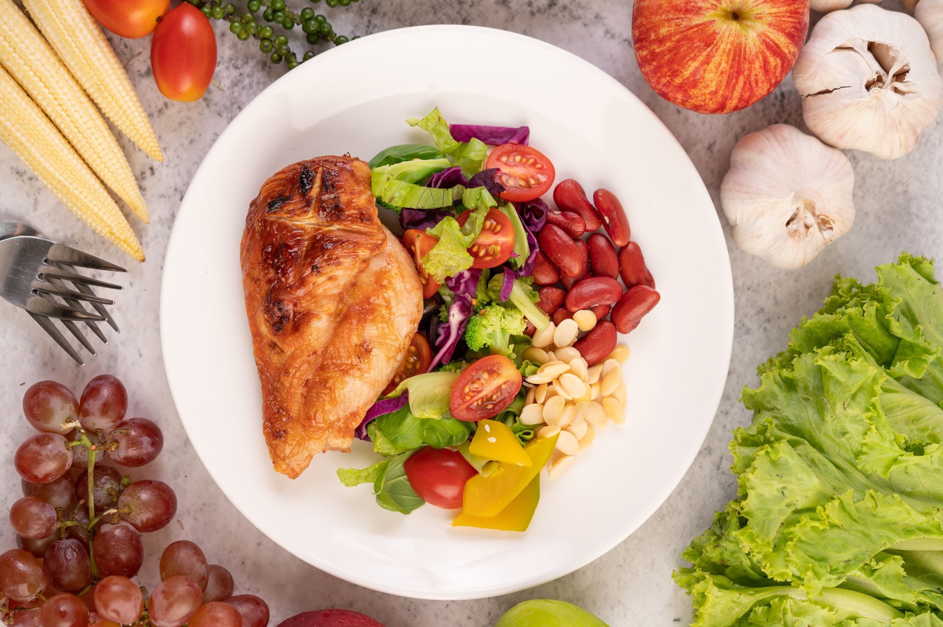 A white plate topped with chicken , beans , vegetables and fruit.