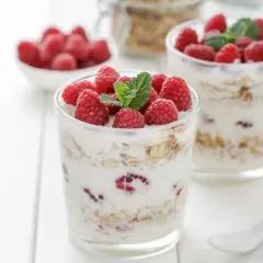 Two glasses of yogurt with raspberries and mint on top