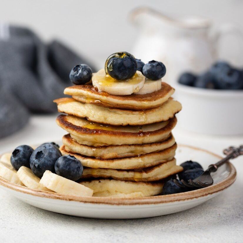 A stack of pancakes with blueberries and bananas on top