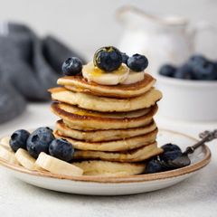 A stack of pancakes with blueberries and bananas on top