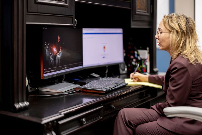 Shellie seated at a desk using a dual-monitor computer in an office setup