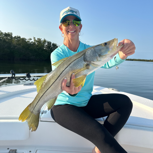 A woman is sitting on a boat holding a large fish