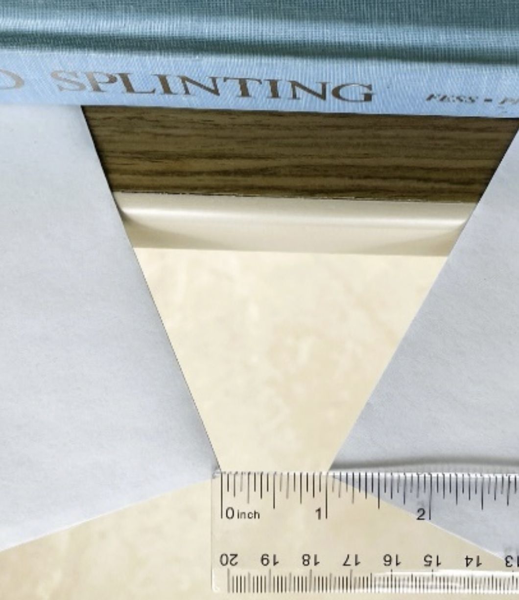 Ruler measuring the gap between two white panels beneath a wooden edge