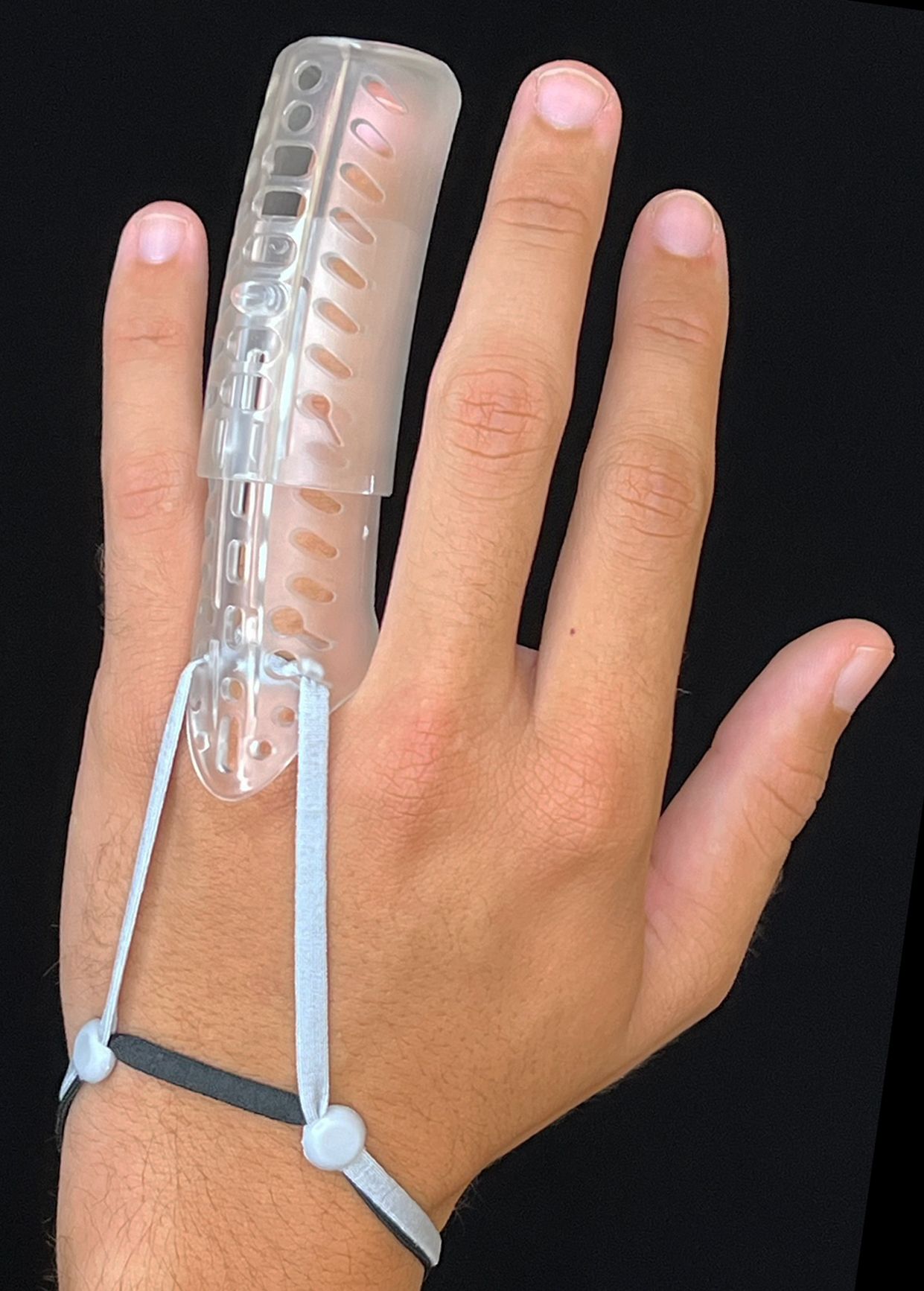 Hand with DigiTube clear wrist brace and black strap against a black background