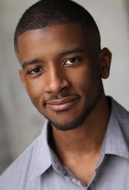 Portrait of a smiling person in a light gray shirt against a soft gray background