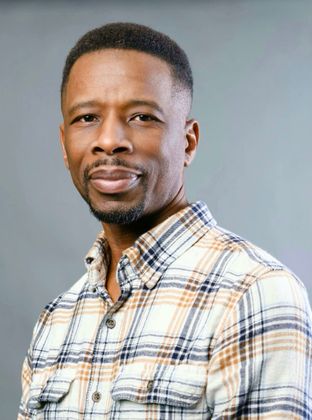 Portrait of a man in a plaid shirt against a gray background