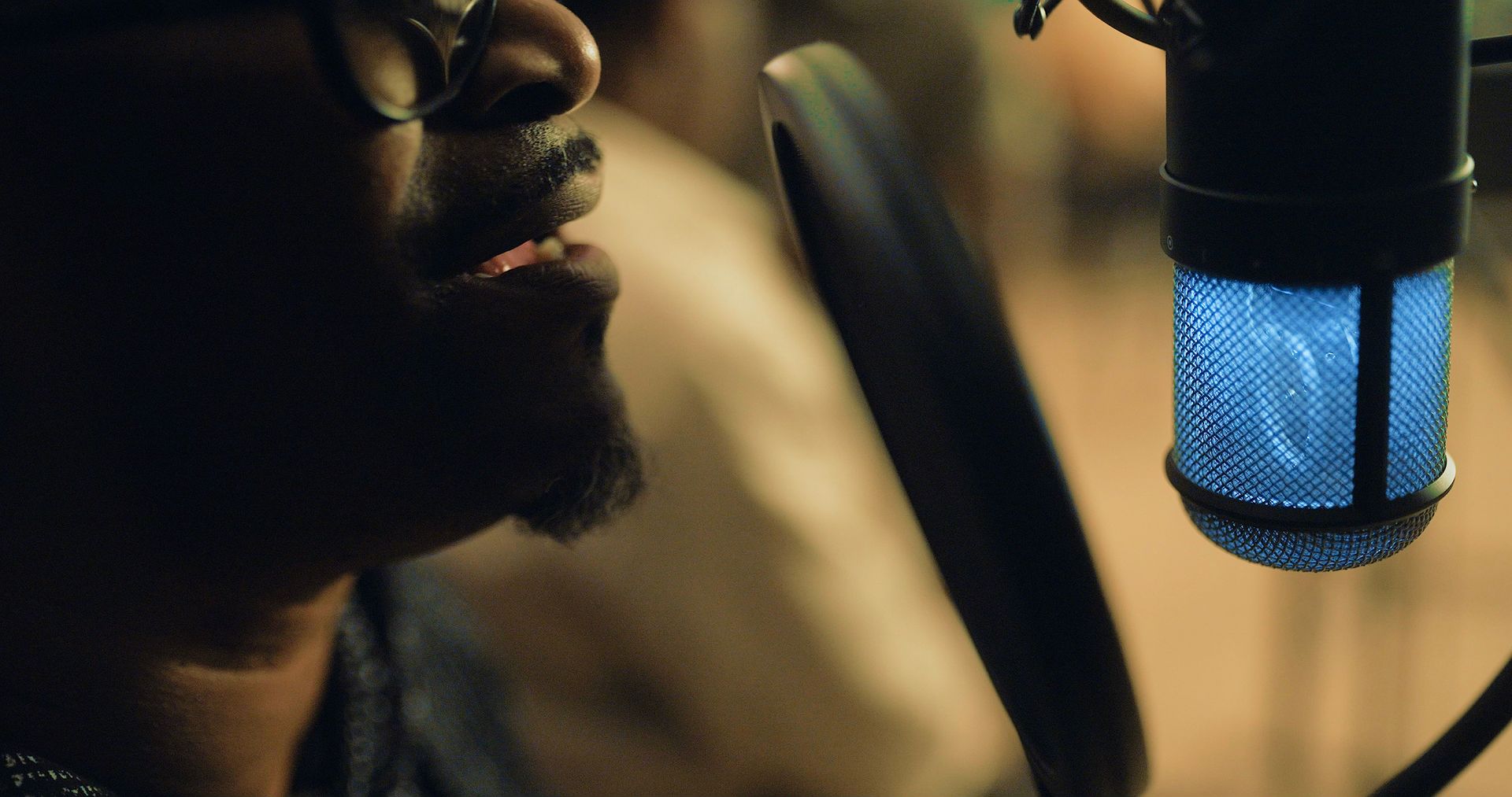 A man is singing into a microphone in a dark room.
