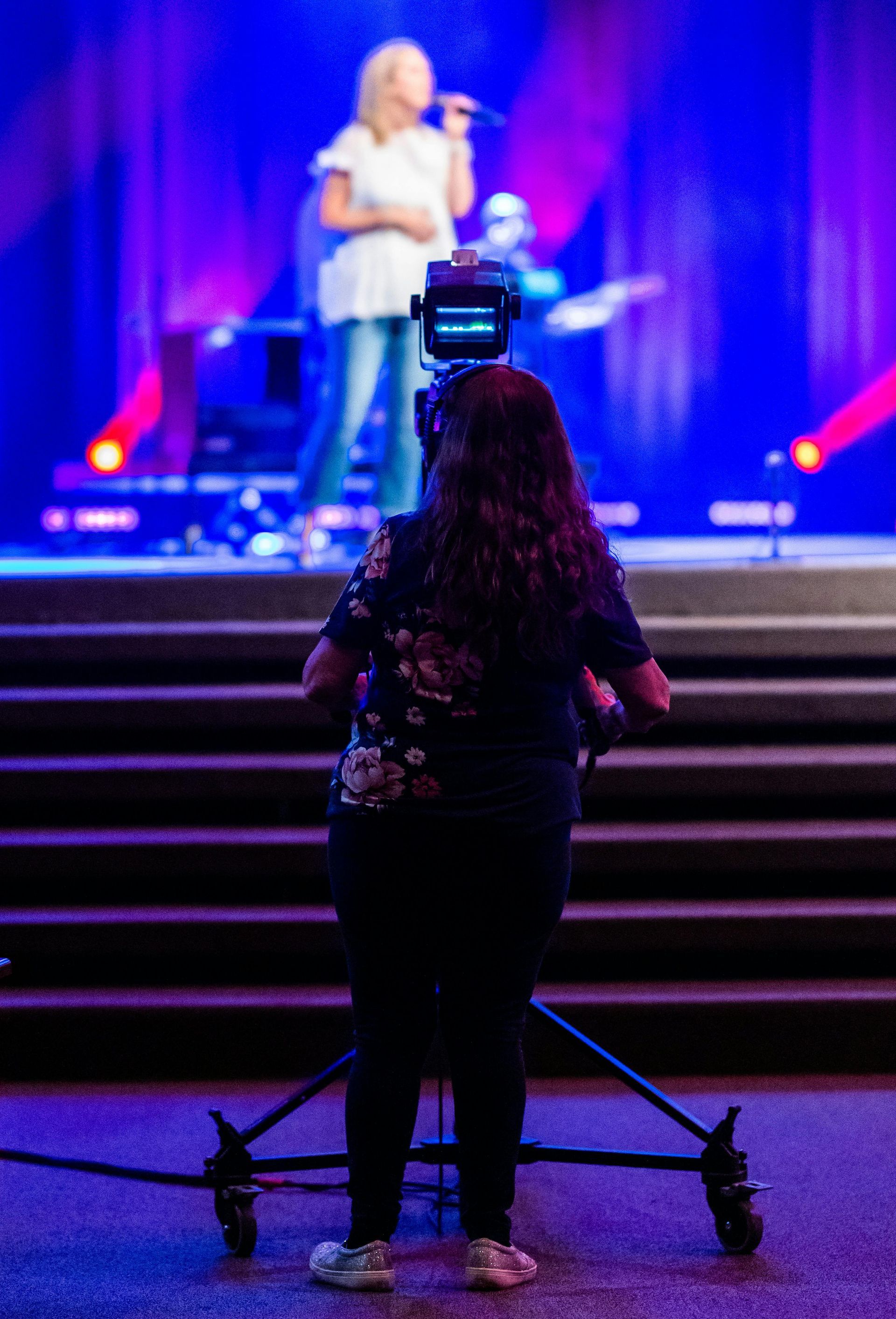 Camera operator filming a performer on a lit stage during a live event