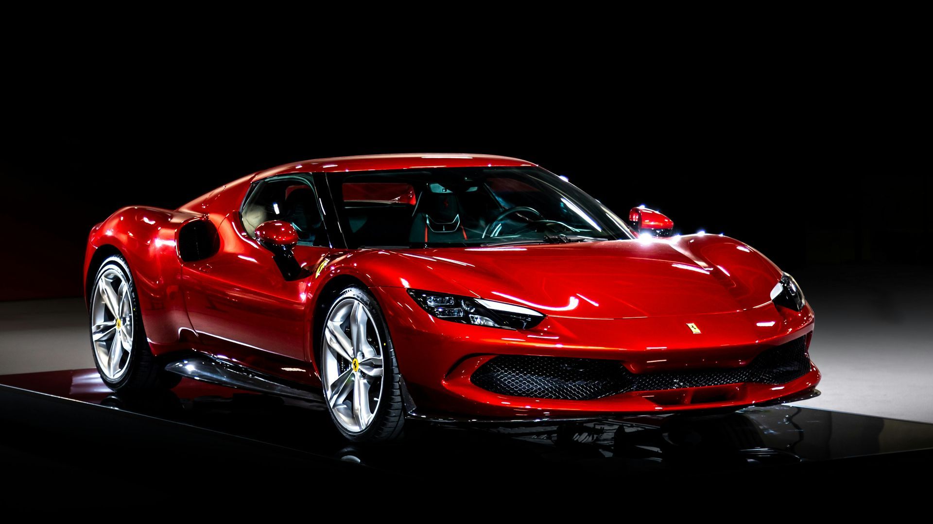 Red Ferrari sports car on display, lit against a dark background.