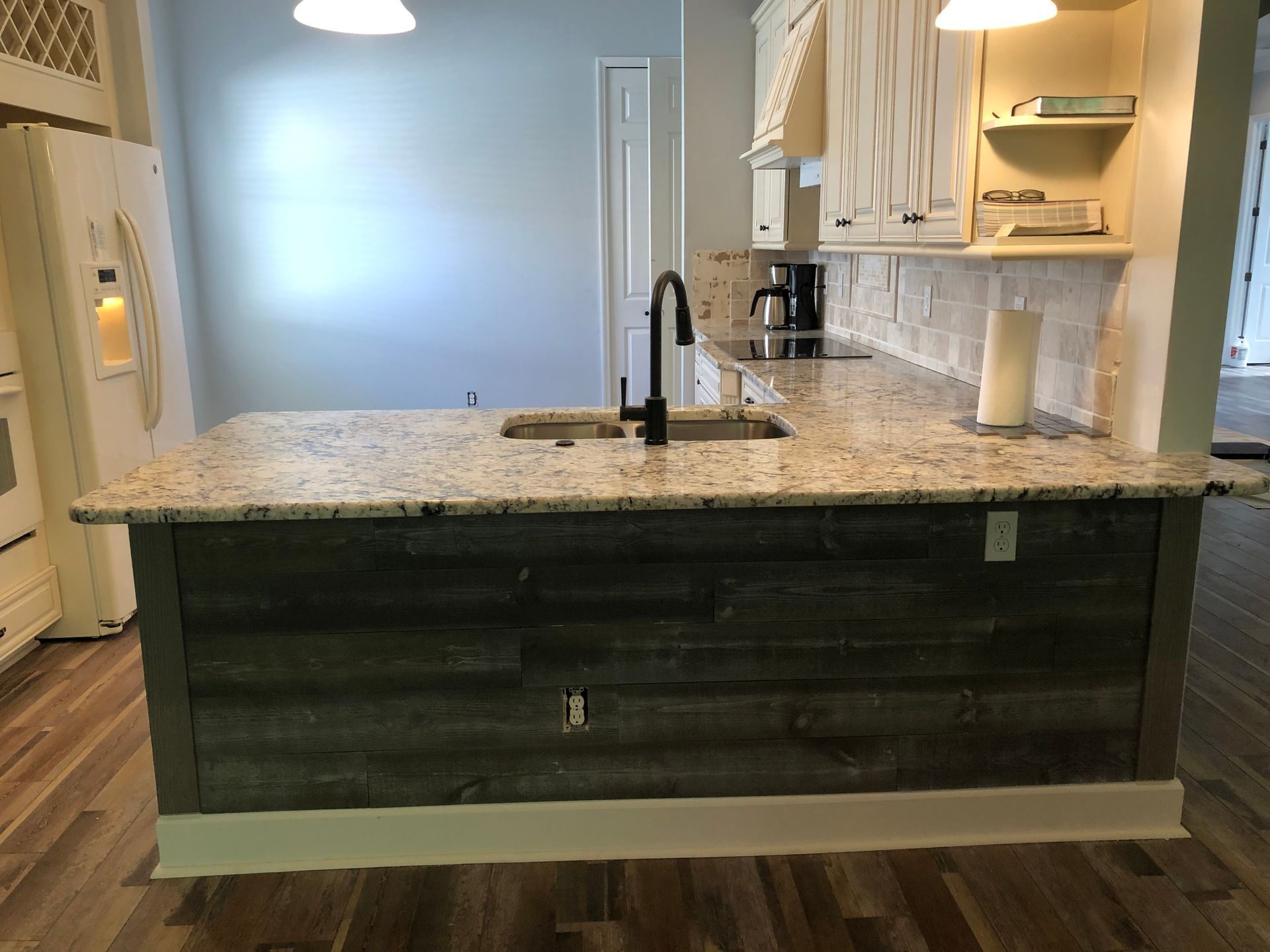 Kitchen island with granite countertop, black cabinets, and a black faucet in a bright modern kitchen