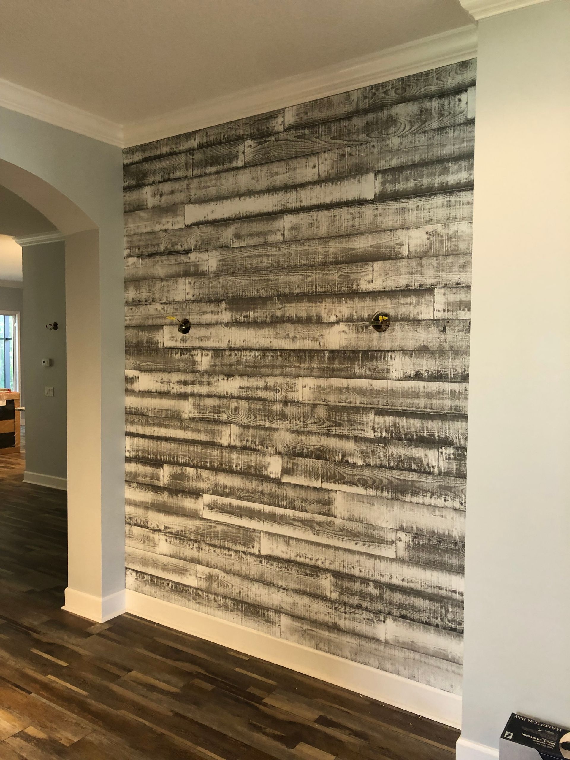 Modern abstract wall art in a hallway with wood flooring and an arched doorway