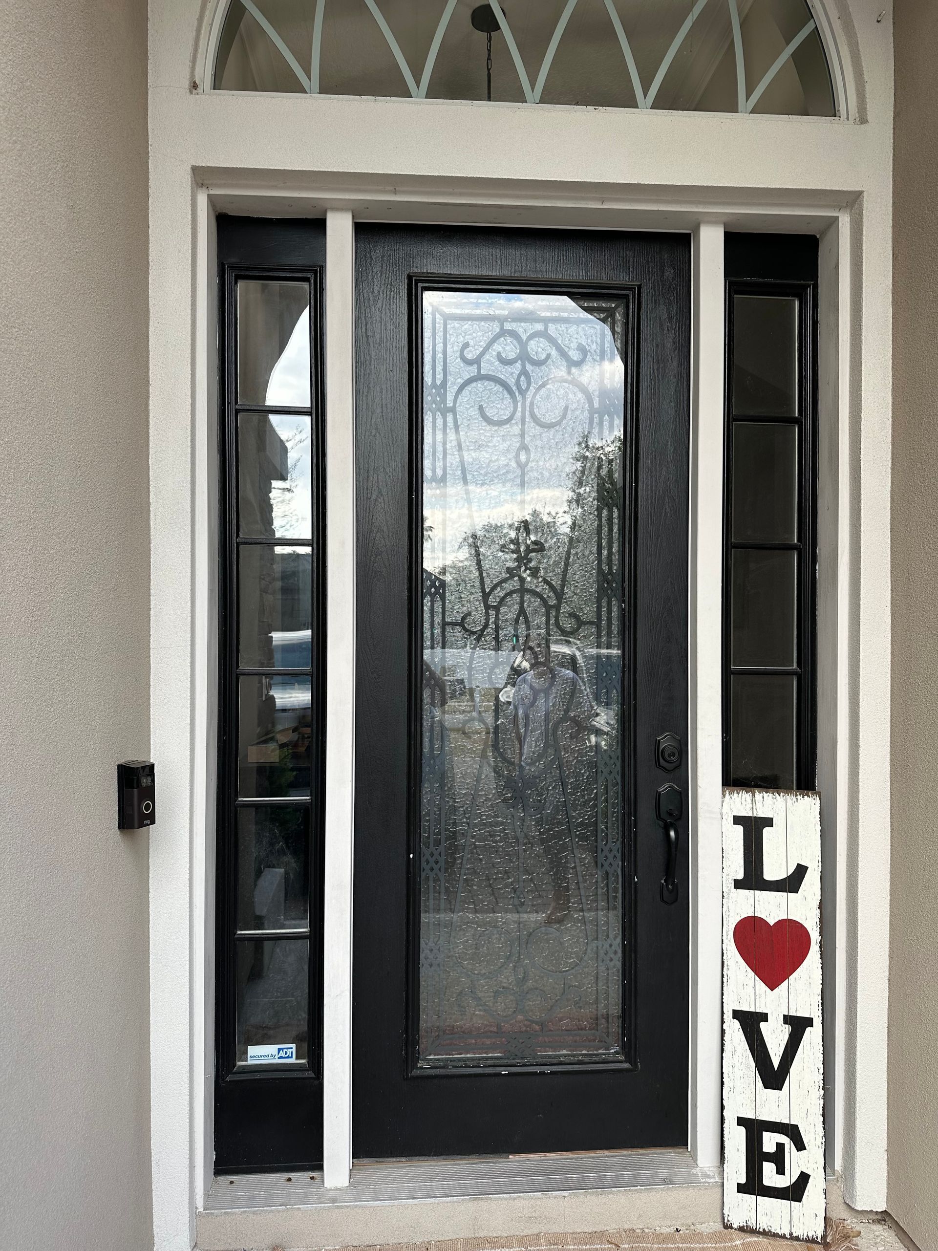Front door with glass panels and a “LOVE” sign beside it