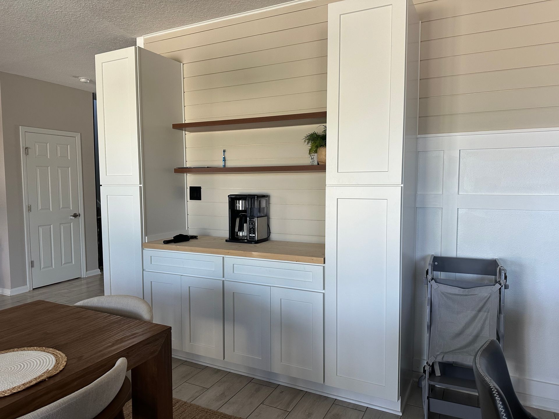 Built-in white cabinets and shelves against a beige wall in a dining room area.