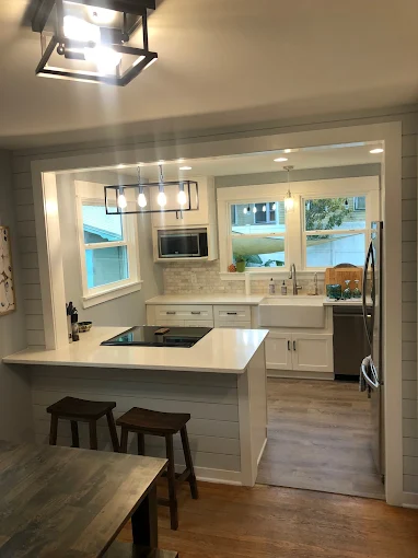 Modern kitchen with white cabinets, large island, pendant lights, and a wood dining table