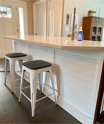 Kitchen island with two white stools and a soap bottle on the counter